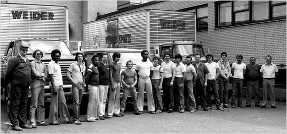 Weider employees standing outside a Weider facility with delivery trucks