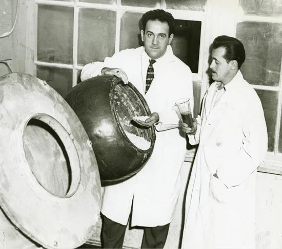 Joe Weider and a colleague in white laboratory coats beside nutrition manufacturing equipment